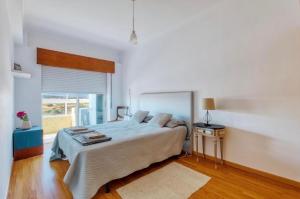 a white bedroom with a large bed and a window at Only 10 min from Lisbon city centre, 15 min driving from the beaches! in Almada