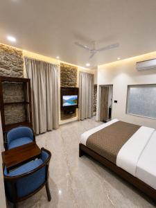 a bedroom with a bed and a chair and a tv at Grand Valley - A Boutique Resort in Mount Abu in Mount Ābu