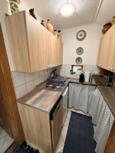 a small kitchen with wooden cabinets and a stove at Berkó Vendégház in Rákóczifalva