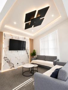 a living room with a couch and a tv on a wall at The Gem - 5 bedroom brand new house in Christchurch