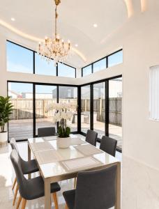 a dining room with a table and chairs and a chandelier at The Gem - 5 bedroom brand new house in Christchurch +9 photos