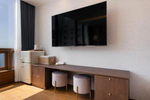 a room with a desk with a television on a wall at Marysol Stay in Busan