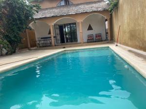a swimming pool with blue water in front of a building at Villa 4 in Saly Portudal