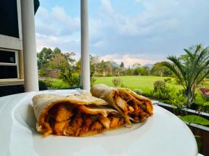 two burritos on a table with a view of a golf course at Ikoro Hotel in Kisoro