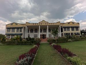 a large building with a lawn in front of it at Ikoro Hotel in Kisoro
