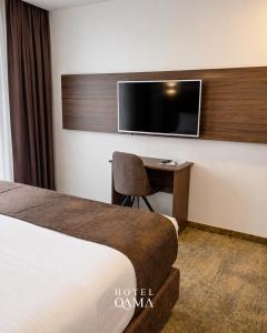a hotel room with a desk and a tv at Qama Hotel in Prishtinë