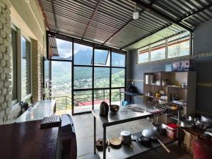 a kitchen with a table and a large window at Penance Homestay in Khokna