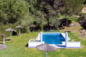 a swimming pool with umbrellas in the grass at Hotel Tugasa Villa de Algar in Algar