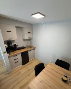 a room with a table and a kitchen at Sunrise Apartamenty in Chocicza