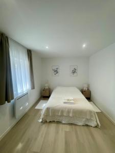 a white bedroom with a bed and a window at La Maison Caroline in Surbourg