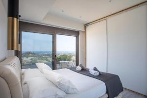 a bedroom with a white bed and a large window at Aetheria Luxury Villa in Kalithies +69 photos