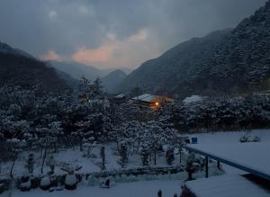 a house in the snow with mountains in the background at Danyang Euljeon 56 Pension in Danyang