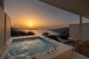 a jacuzzi tub in a house with a sunset at Xenones Filotera in Imerovigli