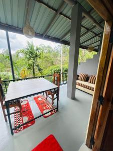 a room with a table and a couch on a balcony at Liana Guest House Ella in Ella