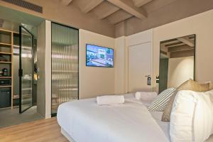 a bedroom with a white bed with a tv on the wall at Andante Princesa in Barcelona