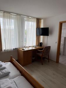 una camera d'albergo con una scrivania, un letto e una camera da letto di Hotel Rademacher a Wittmund Altre 16 foto