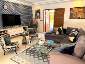 a living room with a couch and chairs and a tv at ORCHID Villa luxueuse avec piscine privée- A 600m de la plage in Pereybere +33 photos