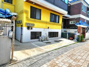 a yellow and white building with a parking lot at SweetJian SweetStay in Suwon