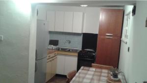 kuchnia z białymi szafkami, lodówką i stołem w obiekcie Apartmani Vilma w Bibinje