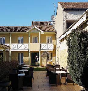un patio avec des tables et des chaises en face d'un bâtiment dans l'établissement Hôtel Les Comtes de Pardiac, à Marciac