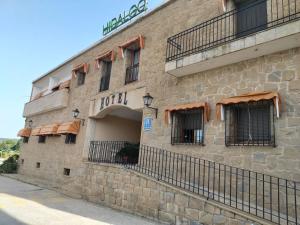 a stone building with windows and a sign on it at HOTEL RURAL HIDALGO in Torreperogil