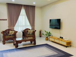 a living room with two chairs and a flat screen tv at 25 Homestay Pulai in Johor Bahru