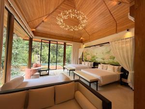 a bedroom with two beds and a couch and a chandelier at AARAWILD Luxury Villas - Sigiriya in Sigiriya