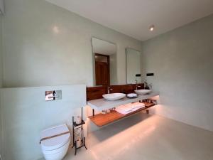 a bathroom with two sinks and a toilet at AARAWILD Luxury Villas - Sigiriya in Sigiriya +54 photos