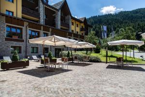 a patio with tables and umbrellas in front of a building at Blu Hotel Acquaseria in Ponte di Legno