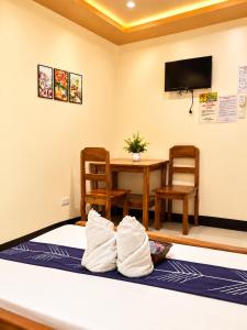 a room with a table and a bed with towels at Buena's Haven Travelodge in El Nido