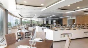 a restaurant with white tables and chairs and a bar at Saipan World Resort in Susupe