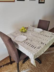 a table with two plates and a bowl of fruit on it at Apartman Angela in Budva