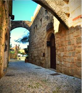 Une allée avec une arche dans un bâtiment en pierre dans l'établissement Petrino, à Rhodes