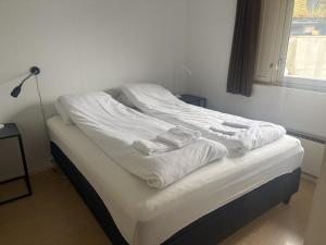 a bed with white sheets and towels on it at Standard Hytte in Fjæra