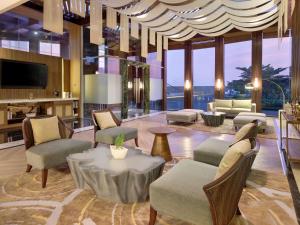 a lobby with chairs and a table and a television at Mercure Pangkalan Bun in Pangkalan Bun