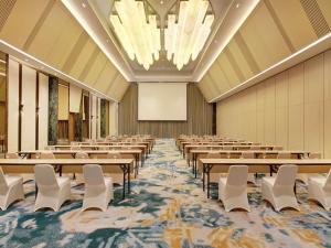 a large room with rows of tables and white chairs at Mercure Pangkalan Bun in Pangkalan Bun +59 photos