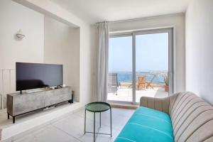 a living room with a couch and a large window at Blu Mar Sea View Apartments in St. Paul's Bay