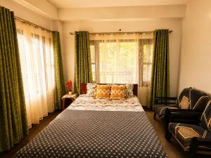 a bedroom with a bed and a couch and windows at Whispering Meadows Luxury 3BHK Villa in Shimla