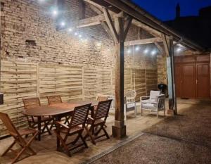 a patio with a table and chairs and a brick wall at Renée-Sens in Châteauvillain