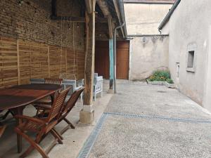 an outdoor patio with a wooden table and chairs at Renée-Sens in Châteauvillain