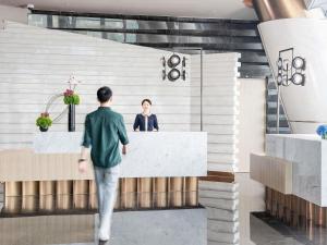 a man walks past a woman at a counter in a lobby at Pullman Shenzhen North in Shenzhen +89 photos