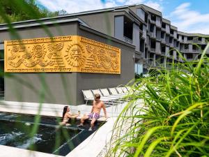 two people sitting on a bench next to a fountain at Minaro Hotel Tokaj - MGallery Collection - Adults Only in Tokaj