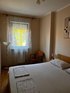 a bedroom with a bed and a window and a chair at Apartman Milkovic 2 in Sombor