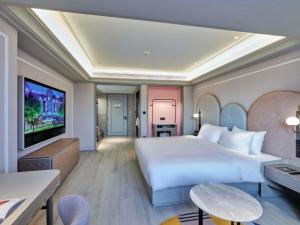 a hotel room with a bed and a flat screen tv at Mercure Lanzhou West in Lanzhou