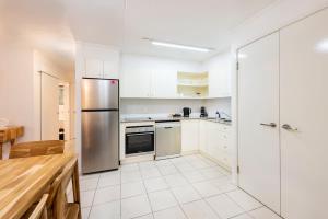 a kitchen with white cabinets and a stainless steel refrigerator at Azure Beach Retreat 2 in Rainbow Beach