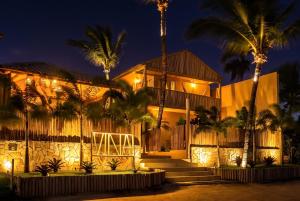 a building with palm trees in front of it at night at Pousada Vina in Jericoacoara