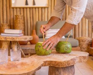 a man is cutting two coconuts on a table at Pousada Vina in Jericoacoara