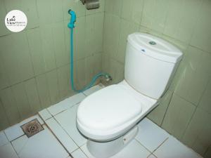 a white toilet in a bathroom with a blue hose at Lake View Dambulla in Dambulla