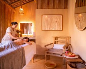 a woman is preparing a man on a bed in a room at Pousada Vina in Jericoacoara