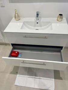 a white sink in a bathroom with a red container at La Maison Caroline in Surbourg +7 photos